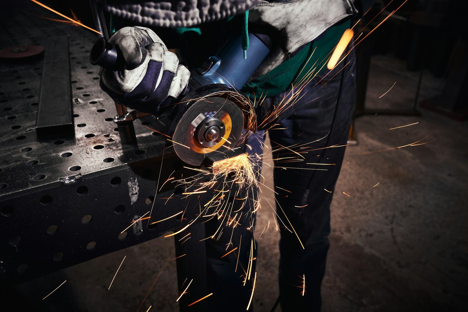 Heavy industry worker cutting steel with an angle grinder.